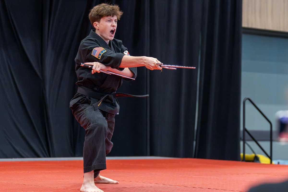 Competitor performing a creative weapons form on stage